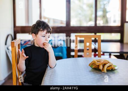 Junge essen Churros am Tisch zu Hause Stockfoto