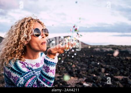 Blonde Frau blasen Konfetti in die Luft, Teneriffa, Spanien Stockfoto