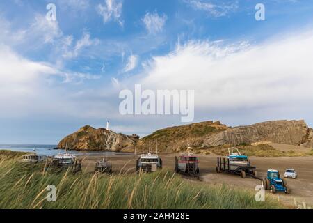 Schiffe am Strand mit Leuchtturm in der Rückseite, Castlepoint, Neue Zwealand Stockfoto