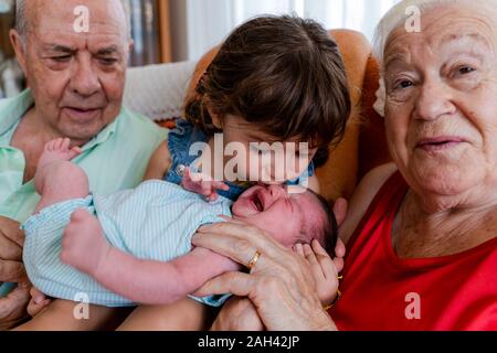 Großeltern mit kleinen Mädchen und Babys zu Hause Stockfoto