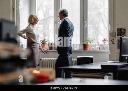 Lächelnd Geschäftsmann und Geschäftsfrau im Gespräch am Fenster im Büro Stockfoto
