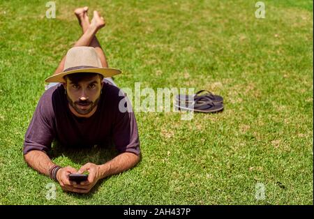 Mann im Gras liegend mit seinem Smartphone Stockfoto