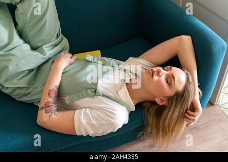 Porträt der jungen Frau auf der Couch liegend, mit geschlossenen Augen Stockfoto