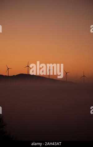 Spanien, Provinz Cadiz, Tarifa, Silhouetten von Windenergieanlagen gegen Moody Sky At foggy Dawn stehend Stockfoto