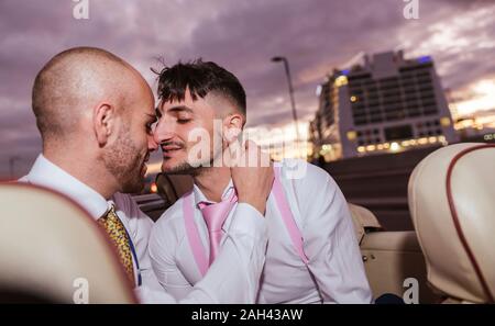 Elegante homosexuelles Paar in einem Oldtimer Cabrio bei Sonnenuntergang Stockfoto