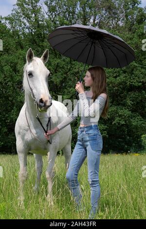 Teenager stehen auf einer Wiese mit Pferd und Dach Stockfoto