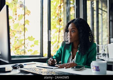 Geschäftsfrau mit Grafiktablett am Schreibtisch im Büro Stockfoto
