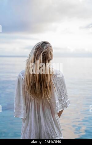 Rückansicht der blonde junge Frau, die vor dem Meer, Ibiza, Balearen, Spanien Stockfoto