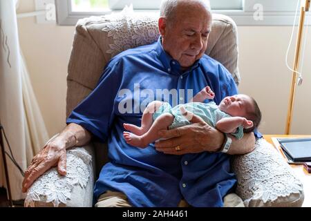 Großvater sitzt in einem Sessel mit einem neugeborenen Baby Stockfoto