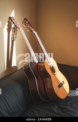 Zwei akustische Gitarren lehnte sich auf der Couch an Sonnenlicht Stockfoto