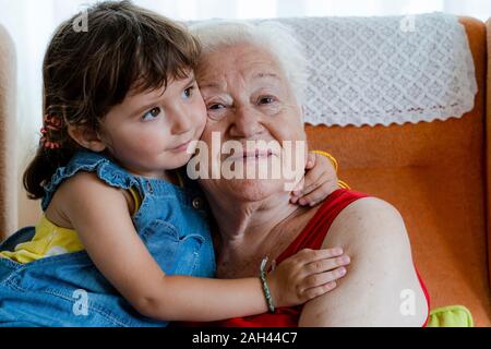 Lächelnde Großmutter ihre Enkelin zu Hause umarmen Stockfoto