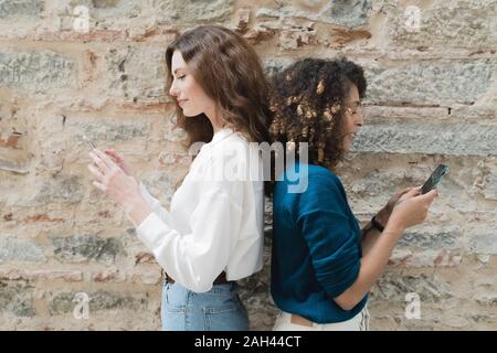 Zwei Frauen stehen mit Smartphones zu sichern Stockfoto