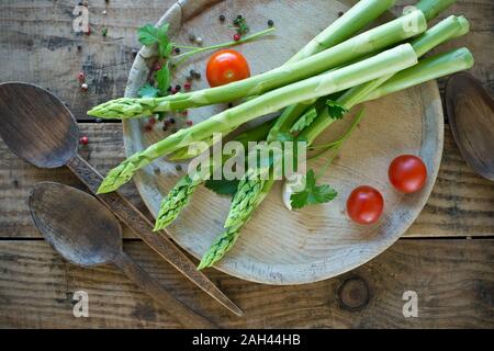 Zwei Kochlöffel und Fach mit frischen Spargel, Tomaten, Petersilie und Pfeffer Stockfoto