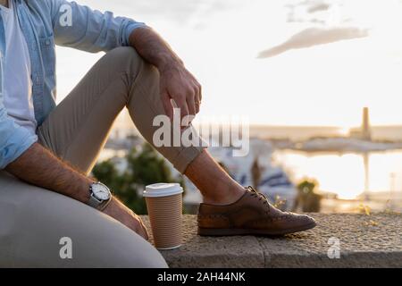 Nahaufnahme der Mann sitzt auf einer Wand auf Ausblick über der Stadt mit Blick auf den Hafen, Barcelona, Spanien Stockfoto