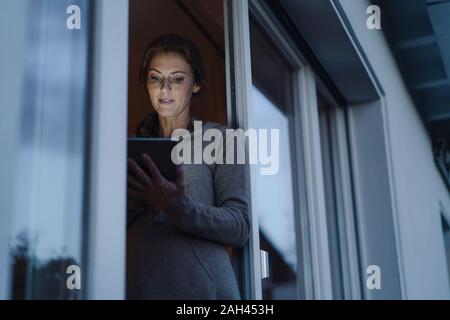 Frau, die in Balkon Tür, mit digitalen Tablet Stockfoto