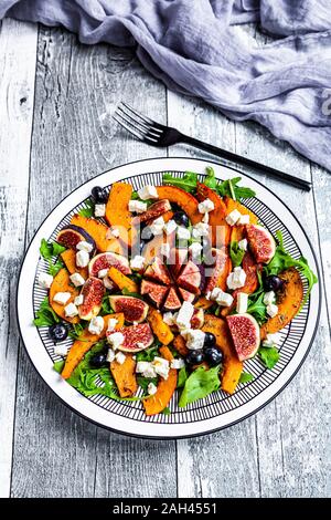 Platte von bunten herbstlichen Salat mit Feigen, Schafskäse, Rucola, Blaubeeren und Hokkaido Kürbis Stockfoto