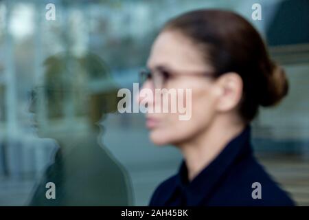 Portrait von reife Frau gespiegelt in Fensterglas Stockfoto