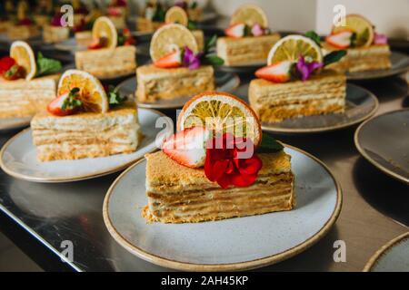 Leckere scheiben Honig Kuchen mit frischen Erdbeeren und frische Blumen auf einem Teller bereit zu dienen. Stockfoto