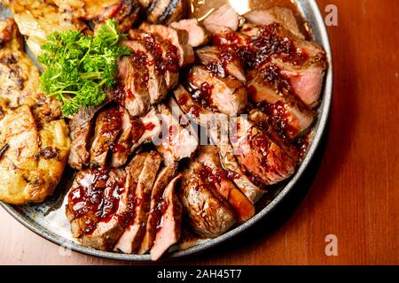 Frische, saftige Sortiment von geschnittenen Fleisch vom Grill, die auf eine große und runde Platte liegt, mit Petersilie auf der Oberseite dekoriert. Stockfoto