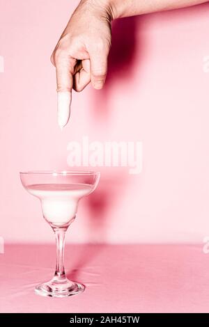 Der Mensch seine Finger eintauchen in eine Flüssigkeit in einem Glas Stockfoto