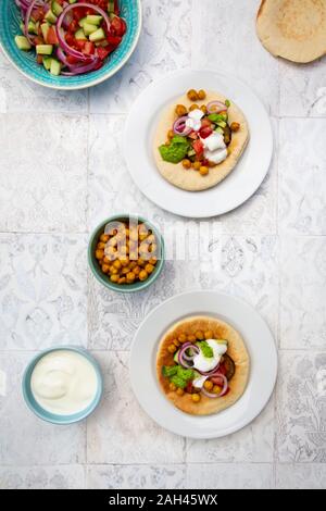 Israelische sabich mit pita Brot, Aubergine, Kichererbsen, Zwiebeln, Tomaten, Gurken, Joghurt und zhug Sauce Stockfoto