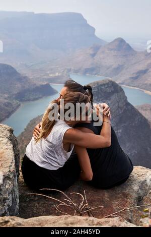 Zwei Frauen umarmen auf einem Felsen mit schönen Landschaft als Hintergrund, Blyde River Canyon, Südafrika Stockfoto