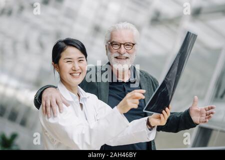 Portrait von Happy älterer Mann umarmt Ärztin Stockfoto