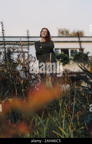 Frau, die vor ihrem Haus, Lookig am Garten Stockfoto