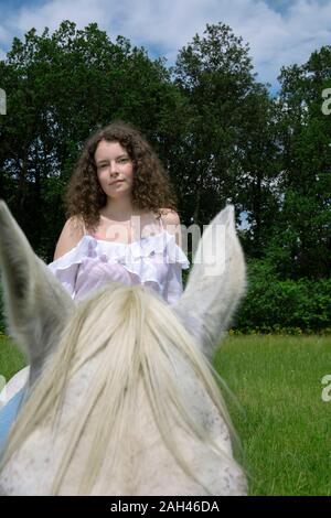 Porträt der jungen Frau sitzt auf Pferd auf einer Wiese Stockfoto