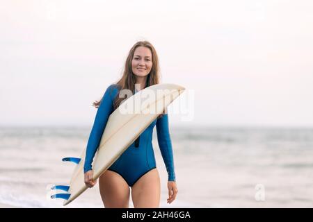 Junge Frau mit Surfbrett am Strand, Strand von Kedungu, Bali, Indonesien Stockfoto