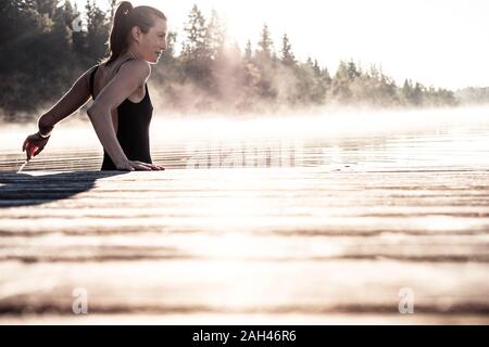 Frau mit schwarzen Badeanzug baden in einem See am Morgen Nebel Stockfoto