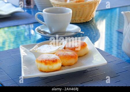 Käsekuchen mit Honig in einem Restaurant. Quark Pfannkuchen oder Quark Krapfen dekoriert Puderzucker in Platte Ansicht schließen. Fit und Ernährung breakfa Stockfoto