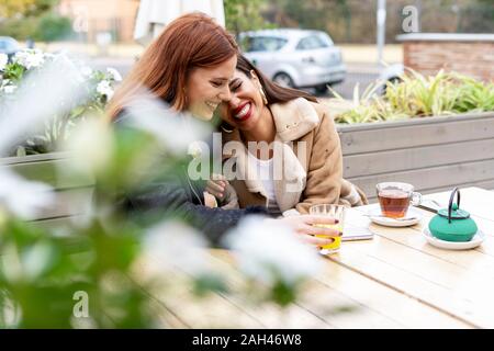 Zwei glückliche weibliche Freunde trinken Kaffee im Freien im Coffeeshop Stockfoto