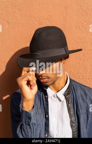 Stilvolle junge Mann mit dem Hut an einer Wand Stockfoto