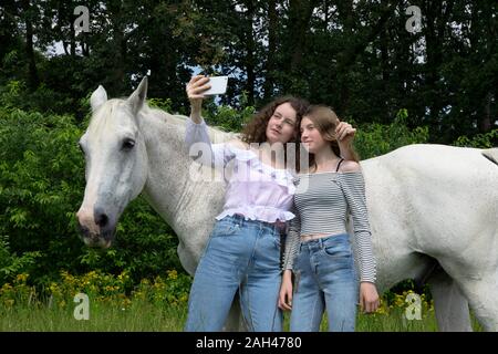 Zwei beste Freunde vor einem Pferd selfie mit Smartphone stehend Stockfoto