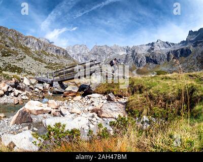 Italien, Provinz Brescia, Adamello Alpen, Val Salarno, Parco regionale dell'Adamello, Wanderer an der hölzernen Brücke Stockfoto