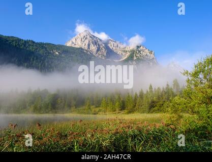 Deutschland, Bayern, Mittenwald, dicker Nebel schweben über Ferchensee See mit wettersteinspitzen Berg im Hintergrund Stockfoto