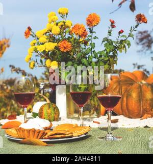 Leuchtend gelbe Chrysanthemen und ein Gläschen Wein Faß auf ein festliches Essen Tisch im Freien. Stockfoto