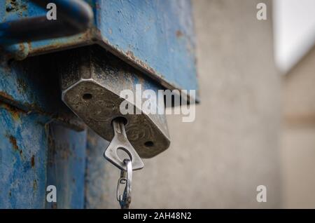 Großes Schloss mit Anti-vandal Schutz. In der Nähe von Schloss auf einem alten Metall Tür. Vorhängeschloss mit Schlüssel in das Schlüsselloch. Schießen von unten nach oben. Stockfoto