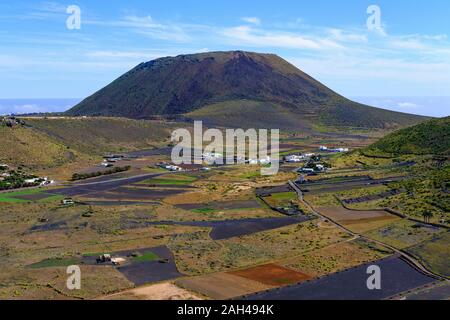 Spanien, Kanarische Inseln, Guinate, Felder vor der ländlichen Dorf mit Monte Corona Vulkan droht in Hintergrund Stockfoto