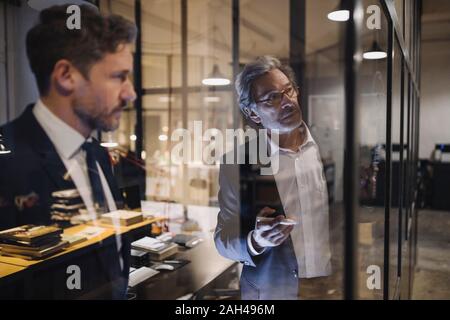 Zwei Geschäftsleute arbeiten auf der Zeichnung auf der Glasscheibe im Büro Stockfoto