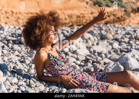 Junge Frau am Strand, Schirmung ihre Augen mit der Hand Stockfoto