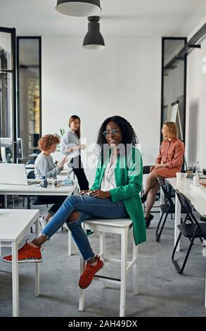 Porträt eines lächelnden Geschäftsfrau sitzen auf Hocker in Office Stockfoto