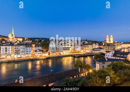 Schweiz, Kanton Zürich, Zürich, Limmat und die Altstadt Gebäude entlang der beleuchteten Limmatquai Strasse in der Dämmerung Stockfoto