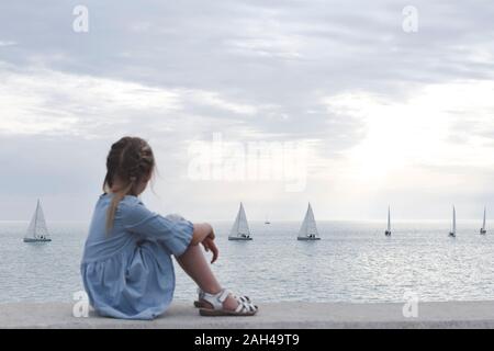 Bisschen Mädchen mit Blick auf das Meer und die Boote Stockfoto