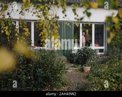 Senior Paar hinter Fensterglas von zu Hause aus suchen Stockfoto