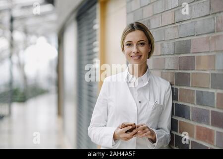 Porträt einer zuversichtlich Ärztin gegen die Wand gelehnt Stockfoto