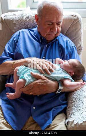 Großvater sitzt in einem Sessel mit einem neugeborenen Baby Stockfoto