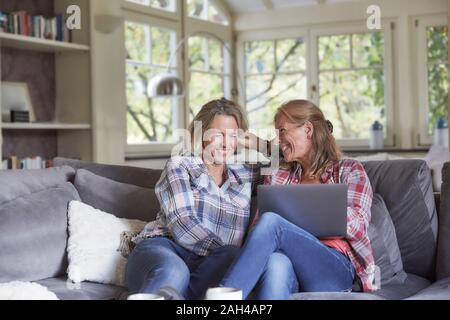 Zwei glückliche reife Frauen mit einem Laptop zu Hause Stockfoto