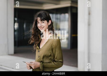 Portrait Of Smiling brunette woman holding Smartphone Stockfoto